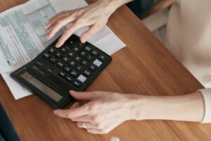 Gros plan d'une femme utilisant une calculatrice et examinant ses factures à la maison.
