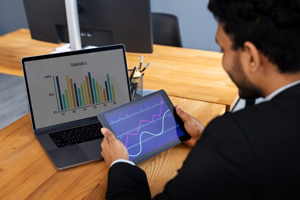 Un homme compare des statistiques sur un ordinateur portable et un graphique interactif sur une tablette, possiblement générés ou analysés avec Galileo AI